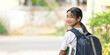 © Prathankarnpap - A schoolgirl is holding painting equipment and carrying a school bag while standing and waiting for a school bus.
