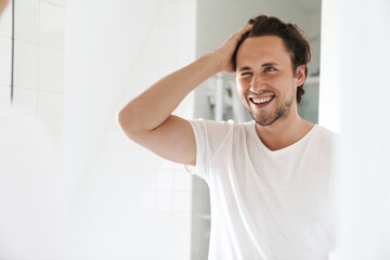 Wall Mural - Attractive young man standing in front of the bathroom mirror