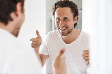 Wall Mural - Attractive young man standing in front of the bathroom mirror