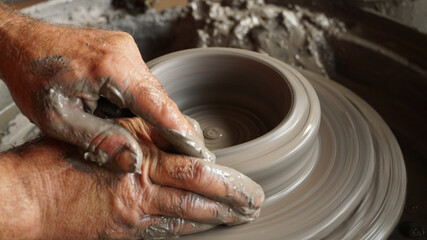 A potter working on a new piece in a pottery studio with clay on his hands in the L'Île-Rousse commune of France on Corsica Island.