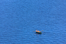 People Rowing A Small Rod Boat On The Big Water