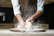 Young woman kneading dough at table in kitchen, closeup