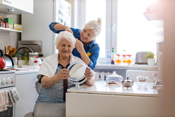 Woman cutting her elderly mother's hair at home
