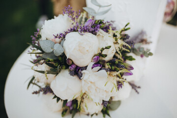 Wedding floristry. On a white wooden table is a bouquet of flowers and greenery