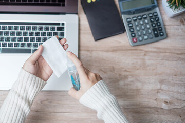 Wall Mural - Woman cleaning laptop by wet wipes tissue and alcohol disinfectant on workplace during working and online learning at home office, protection coronavirus (Covid-19) infection. New Normal concept