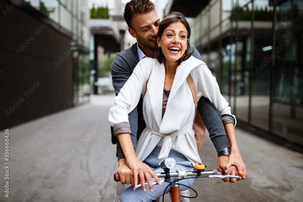 Beautiful happy couple in love on bicycle in the city - obrazy, fototapety, plakaty 