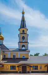 golden-headed Christian church with a bell tower against a blue summer sky