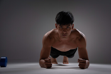 In the fitness,man exercise on training equipmet,use dumbbell  and plank exercise warm up body in gym.