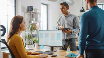 Three Mobile Software Developers Work on Desktop Computer, They Discuss Smartphone Application Design Use Touch Screen Digital Tablet. Modern Stylish Office with Diverse Team of Professionals Working.