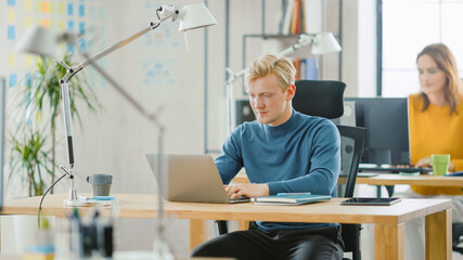 Wall Mural - handsome caucasian it specialist sitting at his desk works on a laptop under his business project. d