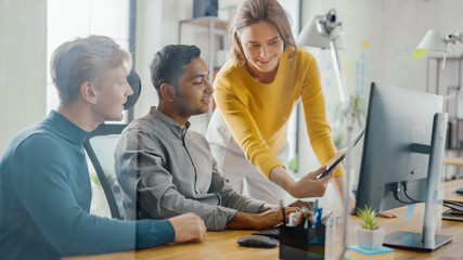 talented entrepreneur working on his desktop computer with project manager and team leader standing 