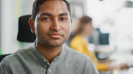 Canvas Print - Portrait of Handsome Professional Indian Man at His Working Desk, Looking at the Camera. Successful Man Working in Bright Diverse Office.