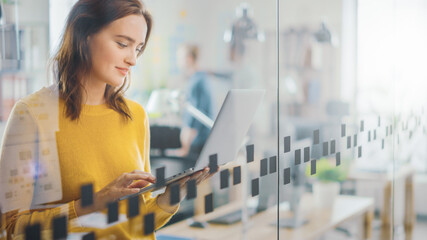 Wall Mural - portrait of beautiful young woman with red hair wearing yellow sweater uses modern laptop while stan