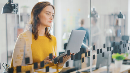 Wall Mural - portrait of beautiful young woman with red hair wearing yellow sweater uses modern laptop while stan