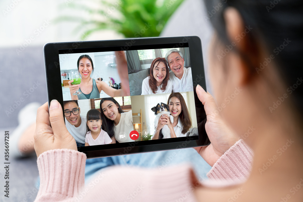 Asian woman talking with family on video call webcam in living room at home  while working from home. Self-isolation, social distancing, quarantine for  protection coronavirus in next or new normal. Stock-bilde |