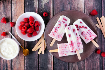 Wall Mural - Raspberry vanilla yogurt ice pops. Top down table scene with a dark wood background.