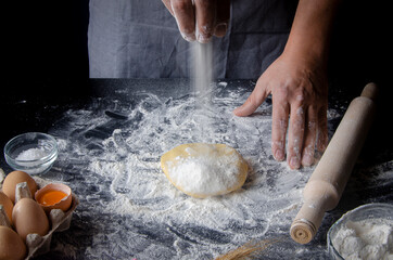 Cook hands kneading dough, sprinkling piece of dough with white wheat flour