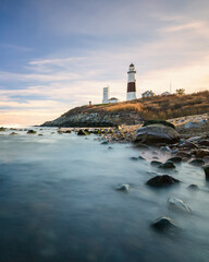 Lighthouse beacon sitting on a cliff overlooking the ocean during sunset. Montauk State Park, New York