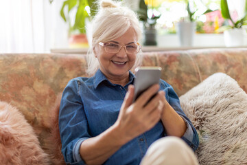 Wall Mural - Senior woman using mobile phone at home
