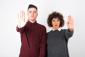 Young beautiful caucasian woman doing stop gesture with palm of the hand. Warning expression with negative and serious gesture on the face isolated over gray background.