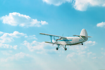 Small old private plane flying in light white clouds