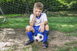 © 3Days2Go Media - Little muddy soccer boy sitting unhappy in front of goal