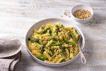 Wall Mural - Vegan pasta with asparagus, garlic, pine nuts and parsley on a wooden background, top view. simple homemade food