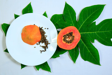 Wall Mural - Tasty sweet ripe sliced papaya fruit and seeds in a white bowl with leaves