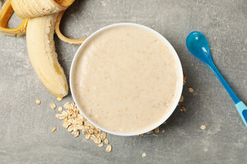 Bowl with porridge on gray background, top view. Baby food