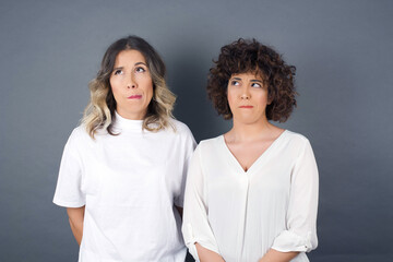 Sticker - Photo of amazed puzzled young Caucasian female with ginger hair knot, curves lips and has worried look, sees something awful in front, isolated on white background, dressed in jean overalls.