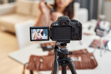 Fototapeta  - Increase your social worth. Asian female blogger showing cosmetic products while recording a tutorial video for her beauty blog using camera at home