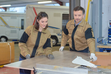 workers cutting out wood panel in campervan garage