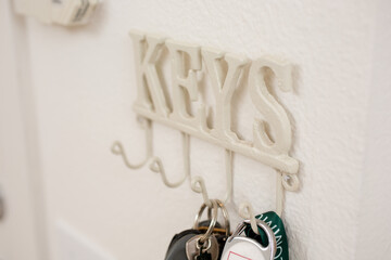 A view of a key hook wall mount with a few hanging keys, in a home setting.