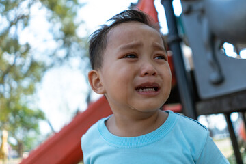 portrait of young small asian boy crying with tear on his face alone in a park