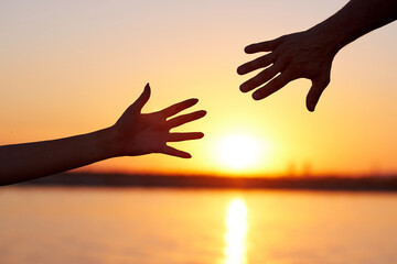 Giving a helping hand. Silhouette Two hands, man and woman, reaching towards each other at sky sunset