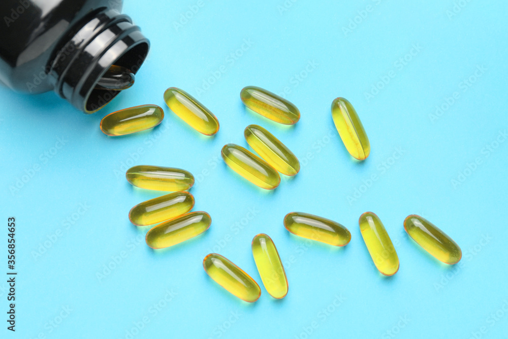 Bottle with fish oil capsules on color background