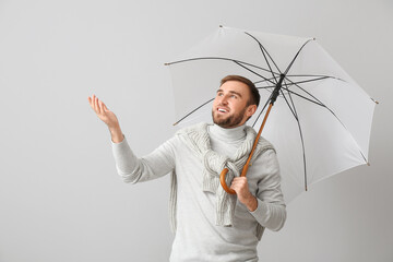 Poster - Handsome young man with umbrella on light background