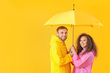 Poster - Happy young couple with umbrella on color background