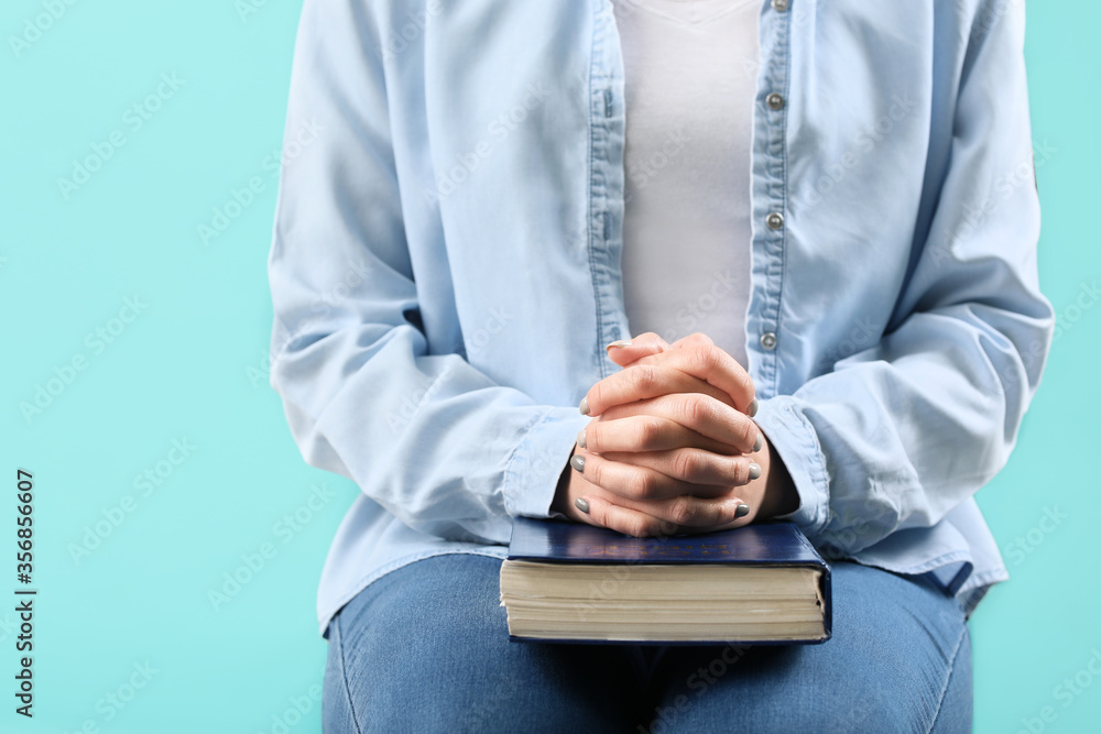 Young woman with Bible on color background