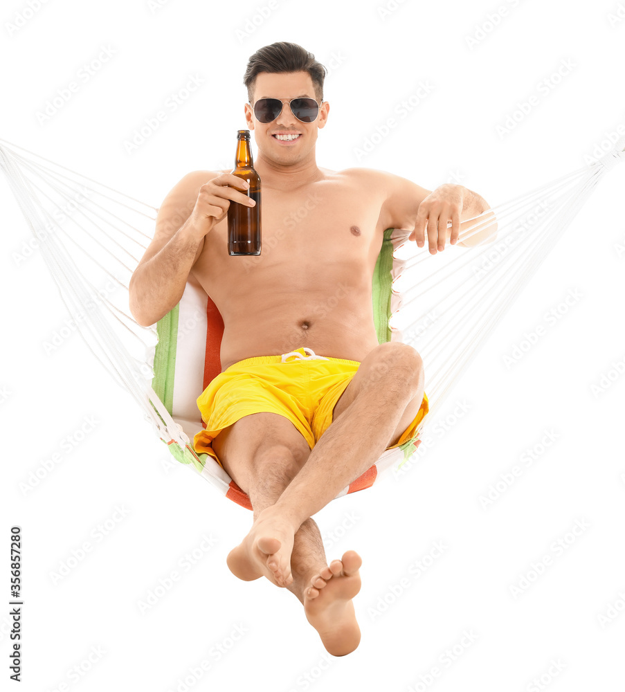 Young man with beer relaxing in hammock against white background
