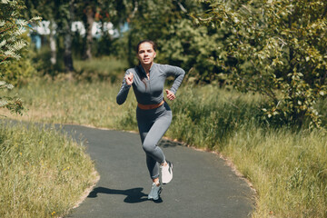 Running girl in city park. Young woman runner outdoor jogging.