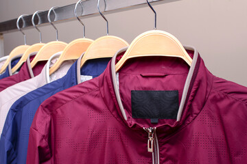 Row of many different colorful hoodie jackets, sport jackets for men and women. Seasonal clothing in store on sale.