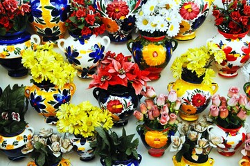 Wall Mural - Ceramic pots/vases with silk flowers displayed on shop wall in a traditional whitewashed village, Mijas, Spain.