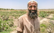 a pakistani farmer with beard working in vegetable fields and smiling 