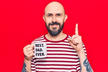 Poster - Young handsome man drinking mug of coffe with best dad ever message surprised with an idea or question pointing finger with happy face, number one