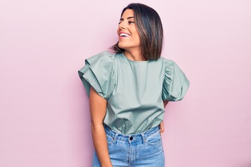 Young beautiful brunette woman smiling happy and confident. Standing with smile on face over isolated pink background