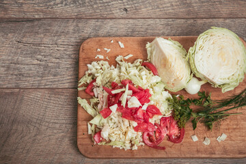 Wall Mural - Fresh organic vegetables, chopped cabbage and tomatoes, greens, dill, parsley on a wooden board and a rustic table, place for an inscription