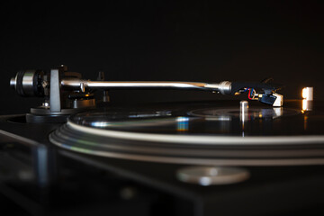 Vinyl record spinning on modern turntable. Black background. Space for text. Play music concept.