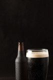 Fototapeta Panele - bottle and glass of cold beer with a red plate on a black background