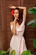 © Svetlana Sokolova - Graceful Asian woman with hibiscus flower in hairs posing over wood wall. Tropical leaves. Summer style.